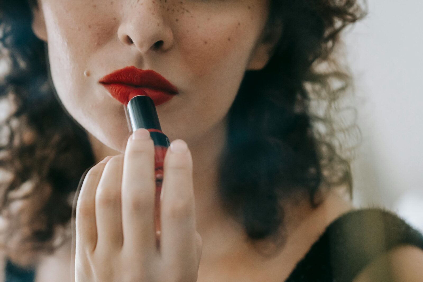 Woman applying red lipstick, close up