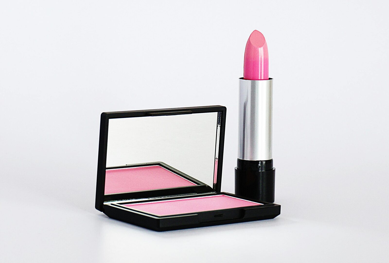 Close-up of pink lipstick and blush on a flat lay